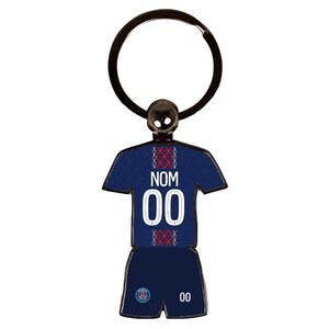 May include: A navy blue keychain in the shape of a soccer uniform. The jersey has the word "NOM" and the number "00" in white. The shorts also have the number "00" in white. The keychain has a black ring.
