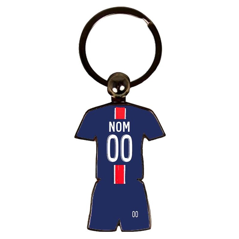 May include: A navy blue keychain in the shape of a soccer jersey with the number "00" in white. The jersey has red stripes and the word "NOM" in white. The keychain has a black metal ring.