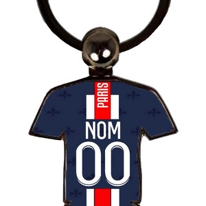 May include: A navy blue keychain in the shape of a soccer jersey. The jersey has the word "PARIS" in red, the word "NOM", and the number "00" in white. The keychain has a black ring.
