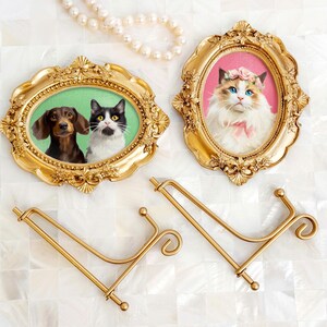 Two vintage-style acrylic pet portraits in ornate gold frames, featuring a Dachshund and a tuxedo cat in one, and a Ragdoll cat with a pink background in the