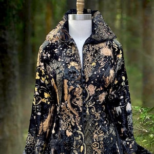 May include: A black jacket featuring an intricate gold and metallic floral pattern, a high collar, and a front button closure. The garment is adorned with textured embroidery, sequins, and lace appliqués throughout the fabric surface.