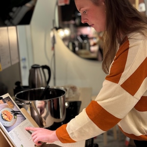 Auf diesem Bild siehst du mich, die Entwicklerin des Saisonkalenders, beim Kochen. Ich lasse mich von den liebevoll gestalteten Illustrationen und Rezeptideen inspirieren, um saisonale Zutaten in leckere Gerichte zu verwandeln.