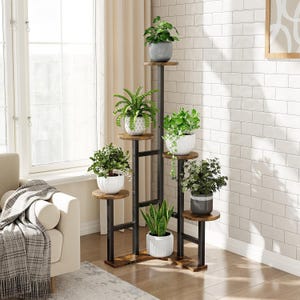 May include: A multi-tiered plant stand with six circular shelves. The shelves are made of wood and supported by a black metal frame. Each shelf holds a potted plant, showcasing a variety of green foliage. The stand is designed for indoor use.