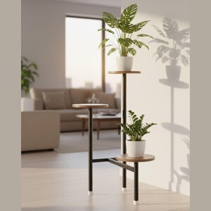 Op de afbeelding: Een plantenstandaard met drie niveaus, met een zwart metalen frame en houten planken. Twee planten in witte potten worden op de standaard getoond. De standaard staat in een goed verlichte kamer.