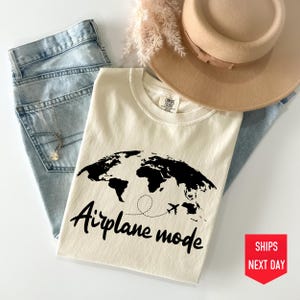 a t - shirt that says airplane mode next to a hat