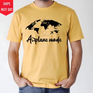 a man wearing a yellow shirt with a map of the world on it