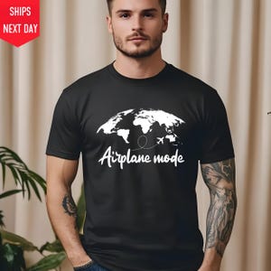 a man wearing a black t - shirt with a map of the world on it