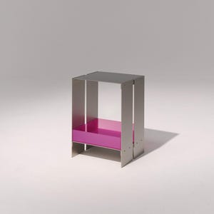 Könnte beinhalten: Ein moderner Beistelltisch mit einem rechteckigen Rahmen aus gebürstetem Metall. Die Oberseite ist dunkelgrau, und der Innenraum hat ein leuchtend magenta Regal. Der Tisch ist etwa 46 cm hoch, 30 cm breit und 30 cm tief.