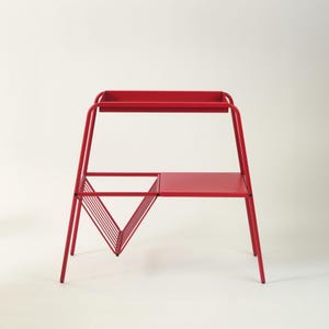 May include: A bright red metal side table with a tray top, a lower shelf, and a triangular magazine rack. The table has a minimalist design and measures approximately 30 inches in height.