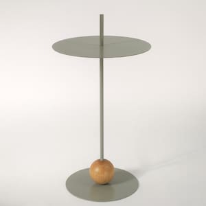 Puede incluir: Una pequeña mesa auxiliar redonda y gris con una base de bola de madera y una tapa circular.