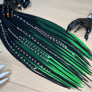 May include: Black and green ombre synthetic dreadlocks with white stitching. The dreadlocks are long and straight.