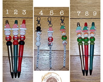 May include: Nine Christmas themed pens with beaded charms. The charms include Santa, a snowman, and elves. The pens are gold, green, and red.