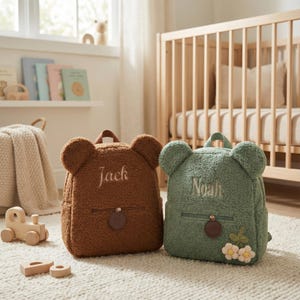 Peut inclure: Deux sacs à dos en peluche en forme d'ours, un marron et un vert. Le sac à dos marron porte la broderie "Jack", et le vert "Noah". Les deux ont des oreilles d'ours, une poche avant et une poignée supérieure.