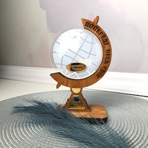 May include: A wooden globe trophy with a clear acrylic globe and a gold plaque that reads "Antropov Taras". The base of the trophy is made of wood and has a gold plaque that reads "Выпуск 2024 Школа №24". The trophy is inscribed with the text "Попереду весь світ".