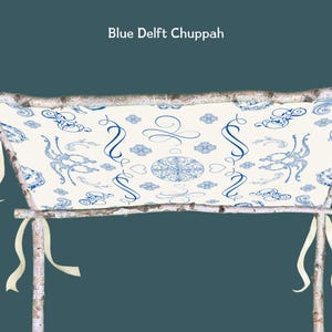 May include: A blue and white chuppah with a Delft design. The fabric is stretched over a birch wood frame and tied with cream-colored ribbons. The fabric features blue floral and scroll patterns.