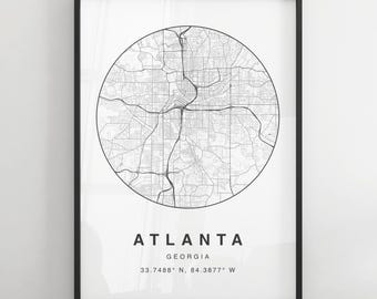 May include: Black and white map print of Atlanta, Georgia. The map is in a circle with the city name and coordinates below. The print is framed in a black frame.