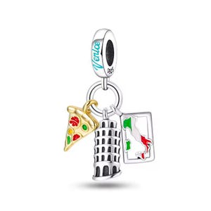 Pode incluir: Berloque de prata com três pingentes com tema italiano: uma fatia de pizza, a Torre Inclinada de Pisa e um mapa da Itália. O berloque tem a palavra "Venice" em verde-azulado e é marcado "S925".