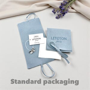 May include: Light blue jewelry packaging with a small charm, a cleaning cloth, and a small pouch with the text "LETOTON Jewelry". The packaging includes a tag with the brand name and product details. The words "Standard packaging" are at the bottom.