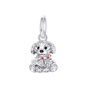 May include: A silver poodle dog charm. The charm features a red collar with red accents and a bow tie with a clear gem. The dog charm is detailed with paw prints and a loop for a necklace or bracelet. The charm is made of silver.