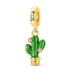 Può includere: Un charm dorato con un design a cactus verde. Il cactus ha due piccoli accenti floreali bianchi e si trova in un vaso dorato. Il charm ha un anello dorato con una piccola gemma bianca ed è contrassegnato con "S925".