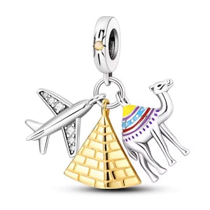 May include: A silver charm bracelet pendant featuring travel-themed charms. The charms include a silver airplane with clear stones, a gold pyramid, and a silver camel with colorful accents. The top charm is a silver bead with a sunburst design.