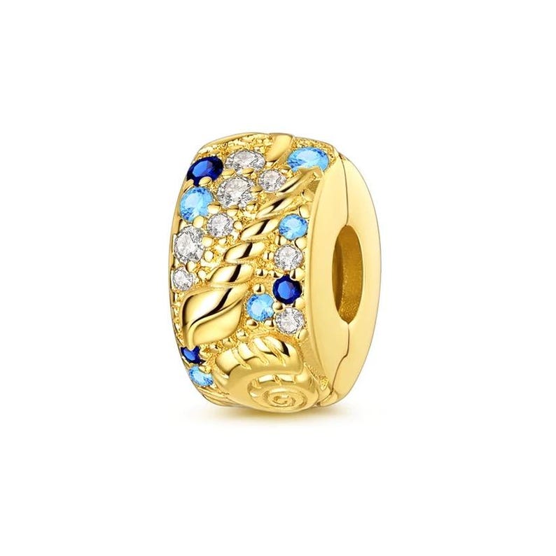 Puede incluir: Un charm dorado con un dise&ntilde;o floral. El charm est&aacute; adornado con piedras preciosas azules, celeste y transparentes. El charm tiene un cierre en un lado y est&aacute; dise&ntilde;ado para ser a&ntilde;adido a una pulsera o collar.