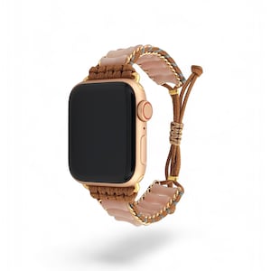 May include: A rose gold Apple Watch with a brown and pink braided strap with a light blue accent. The strap is made of woven cord and has a beaded design.