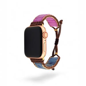 May include: A rose gold Apple Watch with a brown and blue braided strap with pink and blue gemstone accents.