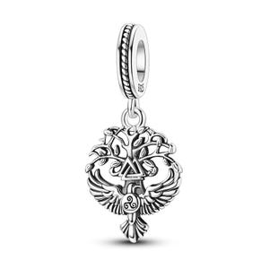 Puede incluir: Un charm de plata con un diseño de árbol de la vida, con un triángulo central y un pájaro con las alas extendidas. El charm tiene un diseño detallado y calado y un lazo para sujetarlo a una pulsera o collar.