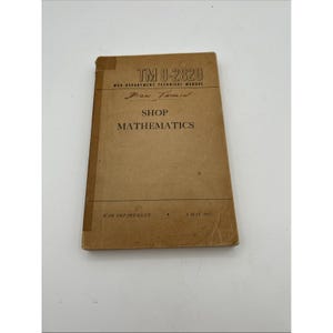 Può includere: Un manuale tecnico del Dipartimento della Guerra color marrone chiaro intitolato TM 9-2820 Shop Mathematics, datato 3 maggio 1943. Il libro con copertina flessibile presenta testo stampato in nero, un dorso marrone scuro e un nome scritto a mano.
