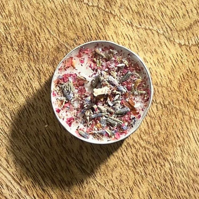 May include: A white candle with dried lavender and rose petals embedded in the wax.