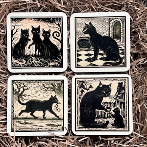 May include: Set of four square coasters featuring black cats in various poses. Each coaster has a white border and a cream background with black and brown illustrations. The coasters feature a cat with a snake, a cat with a bowl, a cat in a doorway, and three cats in a forest.