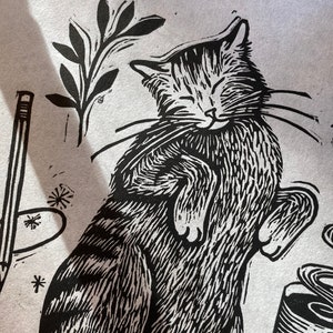 Le confort des créatures Linogravure en relief d'un chat avec du café et un livre plain white kozo