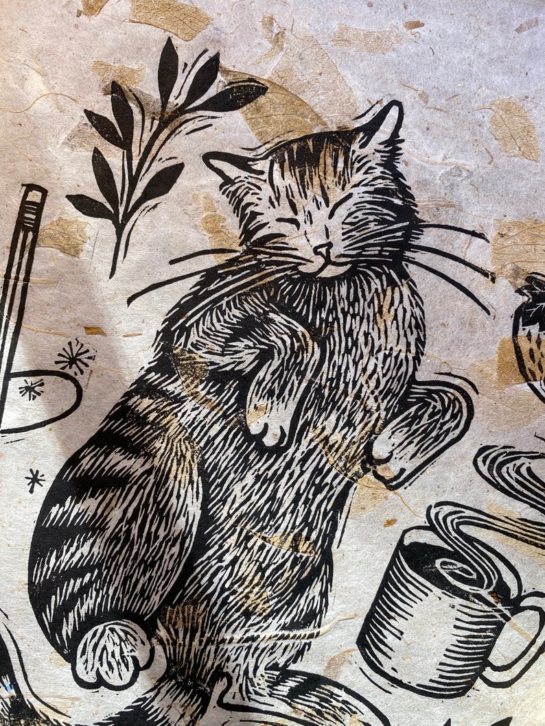 Le confort des créatures Linogravure en relief d'un chat avec du café et un livre natural mango leaf