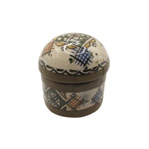 May include: A small, round ceramic trinket box with a lid. The box is beige with a brown rim and features a hand-painted design of blue, yellow, and orange cross-hatch patterns. The lid has a similar design. The box is likely used for storing small items.