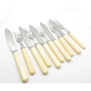 May include: A set of eight silver-plated knives and forks with ivory-colored handles.