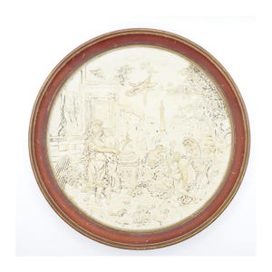 Könnte beinhalten: Eine runde, gerahmte Wanddekoration mit einem erhabenen, weißen, gipsartigen Design, das eine Szene mit Figuren in einer Gartenlandschaft darstellt.