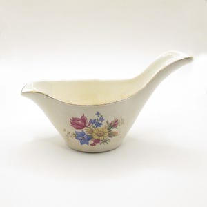 Puede incluir: Juego de tres tazas de cerámica color crema con esmalte moteado. Cada taza presenta un diseño floral pintado a mano en tonos azules, verdes y amarillos. Las tazas tienen una forma simple y redondeada, con un asa.