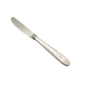 May include: A silver butter knife with a slightly curved blade and a decorative handle. The handle features an embossed floral pattern. The knife is set against a white background.