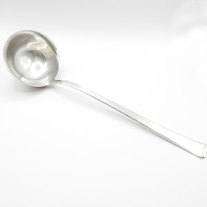 May include: A silver ladle with a long, slender handle. The handle is slightly flared at the end.