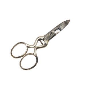 Può includere: Forbici vintage color argento con fori ovali per le dita e un manico curvo. Le lame sono leggermente aperte, mostrando segni di usura. Le forbici sono su sfondo bianco.