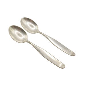 May include: Two silver spoons with rounded bowls and long, slender handles.