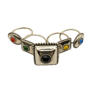 May include: Set of five silver napkin rings with colourful glass stones. The rings are connected and feature a square design with a beaded edge.
