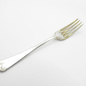 May include: A silver fork with a simple, elegant design. The fork has a rounded handle and four tines.