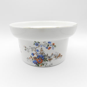 Può includere: Fioriera in ceramica bianca con bordo svasato e un design floreale e paesaggistico dettagliato. Il design presenta fiori blu, arancioni e verdi, una pagoda e un ponte. Il bordo ha un bordo dorato.