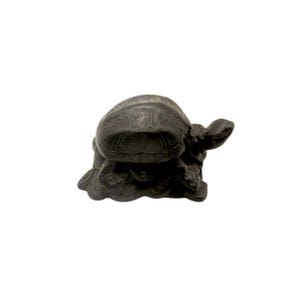 May include: A small, dark-colored turtle figurine. The turtle has a textured shell and is posed on a textured base. The figurine is made of a solid material and is suitable for home decor or as a collectible item.