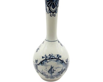 Puede incluir: Un jarrón de cerámica blanco con cuerpo bulboso y cuello largo y delgado. Está decorado con diseños florales y paisajísticos azules, incluyendo una escena con un velero. El borde del jarrón presenta un patrón azul detallado.