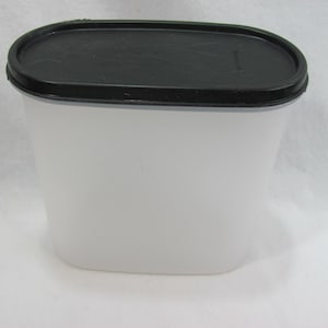 以下が含まれることがあります： 黒い蓋が付いた白い楕円形のプラスチック容器。容器は空です。