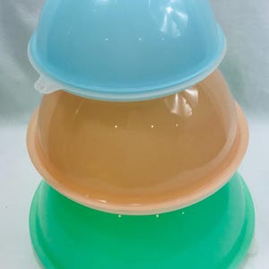 Può includere: Tre ciotole incassate di diversi colori: azzurro, pesca e verde. Le ciotole sono in plastica e hanno una finitura liscia e lucida.