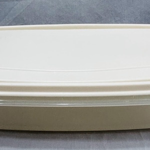 May include: A rectangular, off-white food storage container with a matching lid. The container has rounded corners and a slightly transparent band around the base. The lid sits flush, creating a clean, simple design.